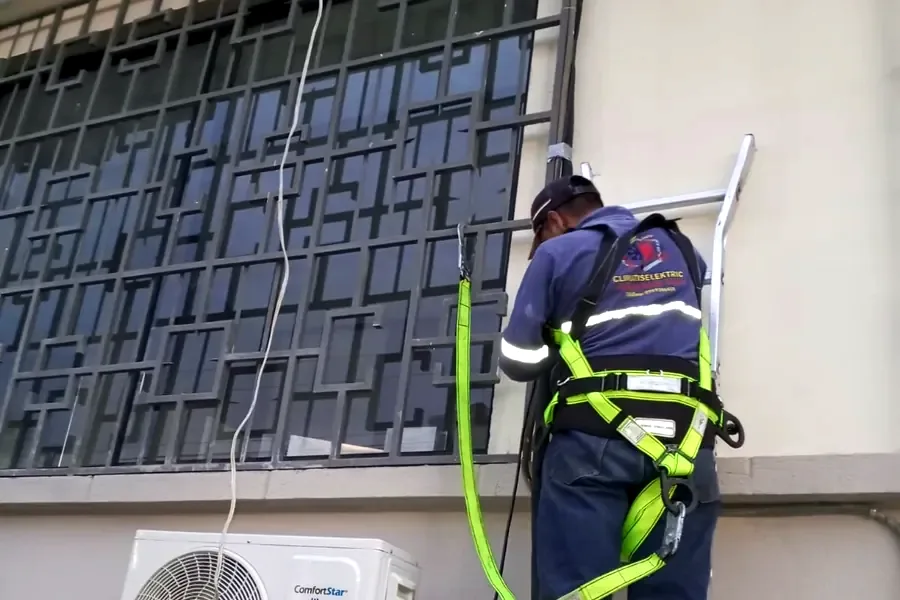 Técnico de Climatiselektric con arnés de seguridad instalando un aire acondicionado split en fachada